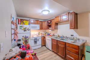 Kitchen featuring white appliances, wood finish cabinetry, light wood-type flooring, and light countertops