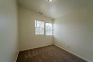 Unfurnished room with dark colored carpet and baseboards