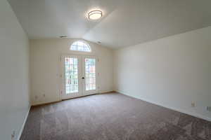 Empty room with carpet, french doors, and a textured ceiling