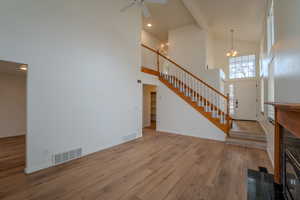 Unfurnished living room featuring light wood-type flooring, vaulted ceiling, a ceiling fan, and hanging lights