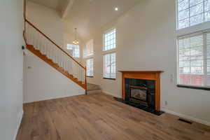 Unfurnished living room with light wood finished floors, a fireplace, lofted ceiling, and a chandelier