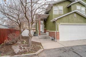 View of front of property with stucco siding, brick siding, and driveway
