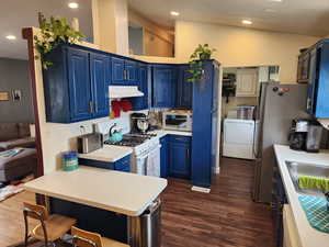 Kitchen featuring blue cabinetry, light countertops, stainless steel appliances, a breakfast bar, and dark wood-type flooring