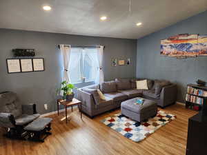 Living room featuring light wood-style floors, recessed lighting, and a textured wall