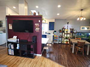 Living area with light wood-type flooring and suspended lighting