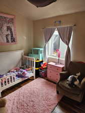 Bedroom featuring a textured wall, wood finished floors, and a textured ceiling