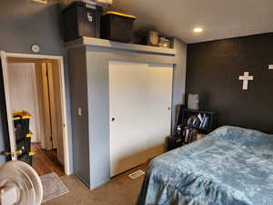 Bedroom with a textured wall, dark colored carpet, a closet, and recessed lighting