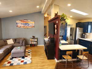 Kitchen featuring light countertops, lofted ceiling, light wood finished floors, recessed lighting, and stainless steel fridge