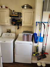 Laundry room featuring cabinet space, separate washer and dryer, and dark wood-style flooring