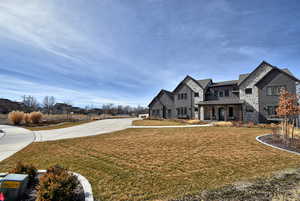 View of front facade with a standing seam roof, a front yard, a porch, and stone siding