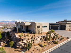 Southwest-style home with stucco siding, an attached garage, a mountain view, driveway, and a patio area