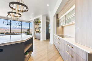 Two tone kitchen featuring open shelves, light wood-style flooring, light stone countertops, modern cabinets, and two tone cabinetry