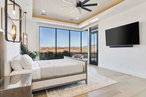Bedroom featuring light wood finished floors, a tray ceiling, access to outside, a ceiling fan, and recessed lighting