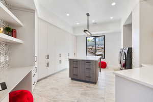 Kitchen with two tone color scheme, a kitchen island, open shelves, recessed lighting, and washing machine and clothes dryer