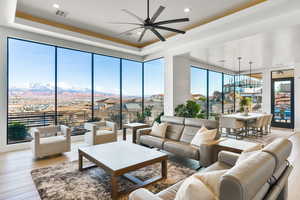 Living room with a ceiling fan, light wood finished floors, a tray ceiling, and a mountain view