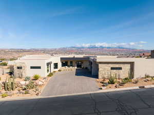 Pueblo revival-style home featuring stucco siding, a mountain view, a patio area, and stone siding