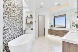 Full bathroom with vanity, a freestanding tub, built in shelves, light tile patterned floors, and tile walls