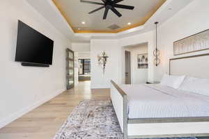Bedroom featuring light wood-type flooring, a raised ceiling, recessed lighting, and ceiling fan