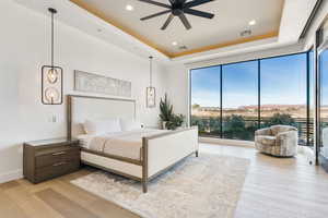 Bedroom featuring a raised ceiling, recessed lighting, light wood-style flooring, and ceiling fan