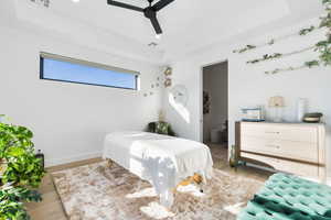 Bedroom featuring a raised ceiling, wood finished floors, ensuite bath, ceiling fan, and recessed lighting