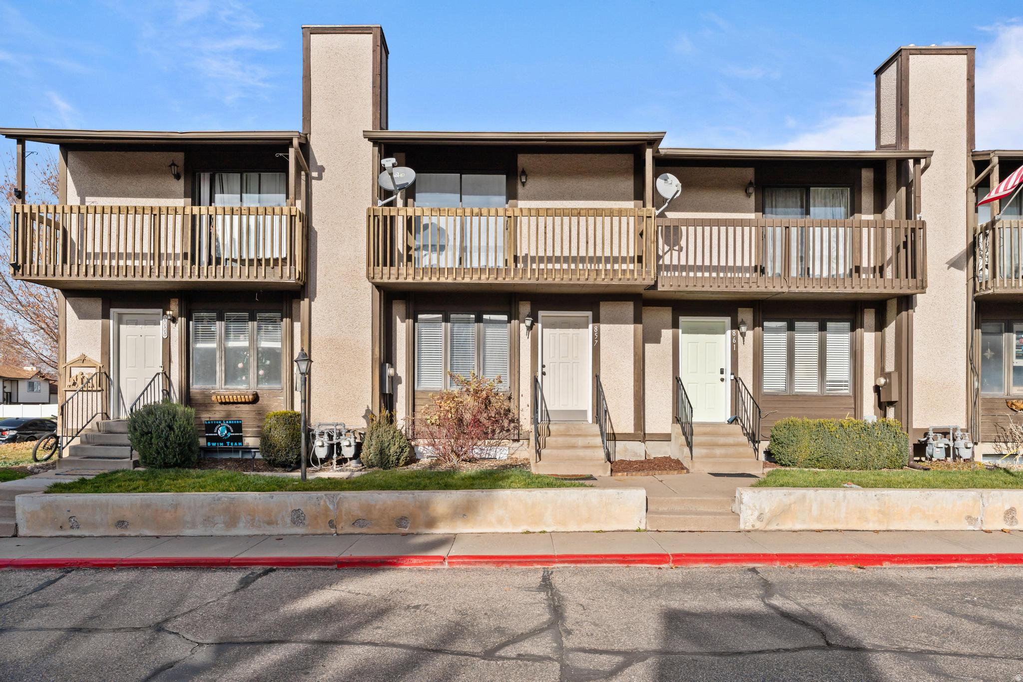 View of front of house with a chimney, a balcony, stucco siding, and entry steps