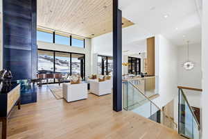 Greeted by White Oak Flooring, Wood Ceiling, Metal Fireplace Surround, and Floating Staircase with Glass Railing