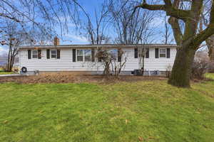 Ranch-style home with a chimney and a front lawn