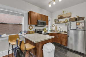 Kitchen featuring stainless steel appliances, wood finish cabinets, a peninsula, and a kitchen bar