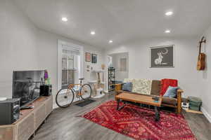 Living room featuring wood finished floors, vaulted ceiling, and recessed lighting