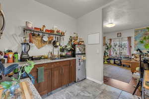 Kitchen featuring wood finish cabinets, freestanding refrigerator, open shelves, and light tile patterned floors