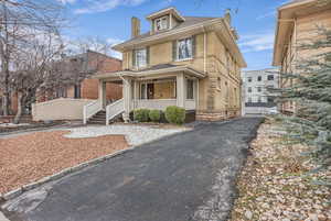 Traditional style home with a chimney, a porch, brick siding, and roof with shingles