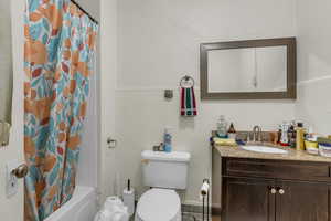 Full bathroom with shower / bath combination with curtain, vanity, a wainscoted wall, and tile walls