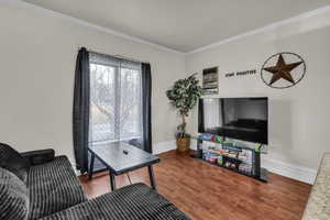 Living room featuring dark wood finished floors and crown molding