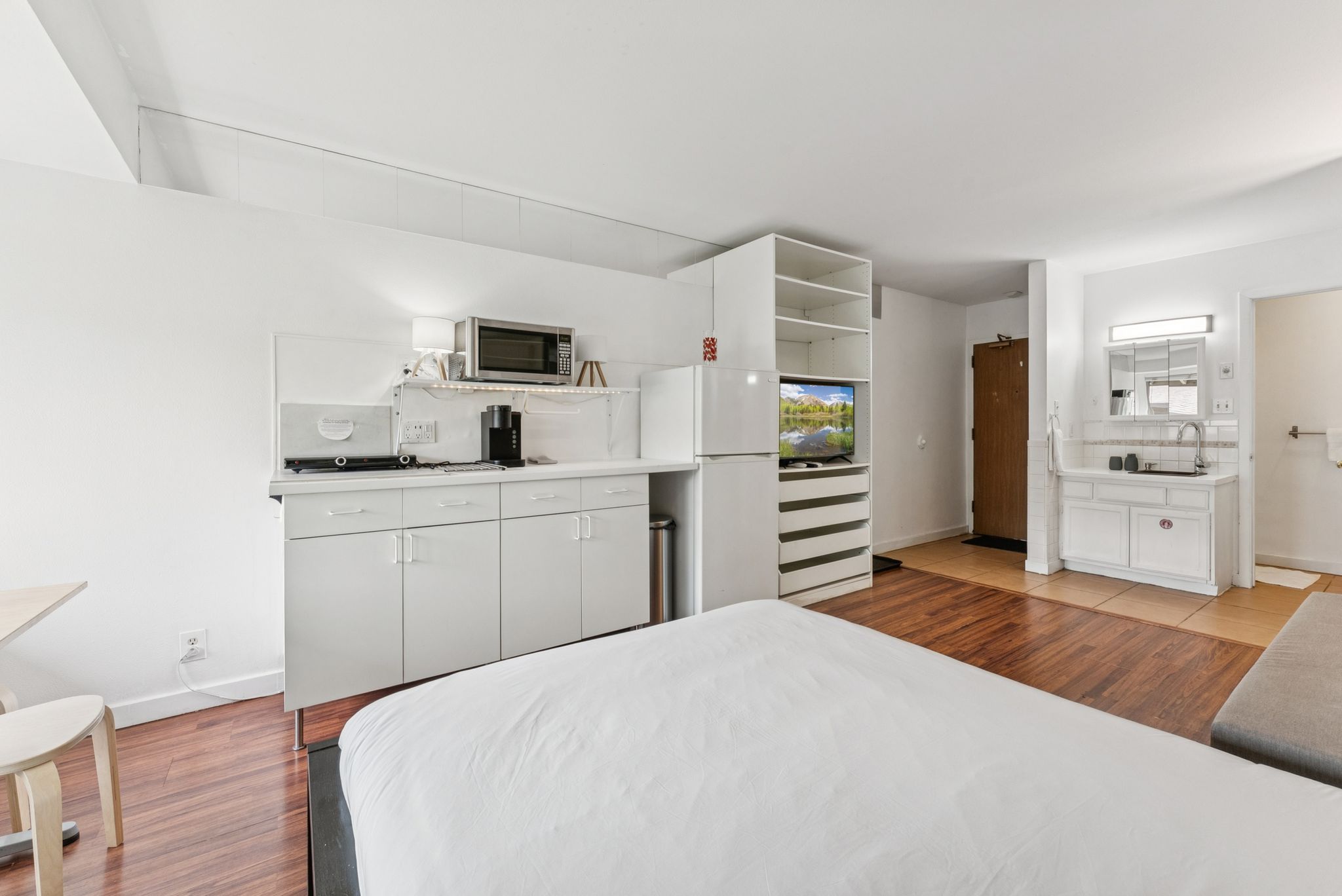 Bedroom with light wood-type flooring and freestanding refrigerator