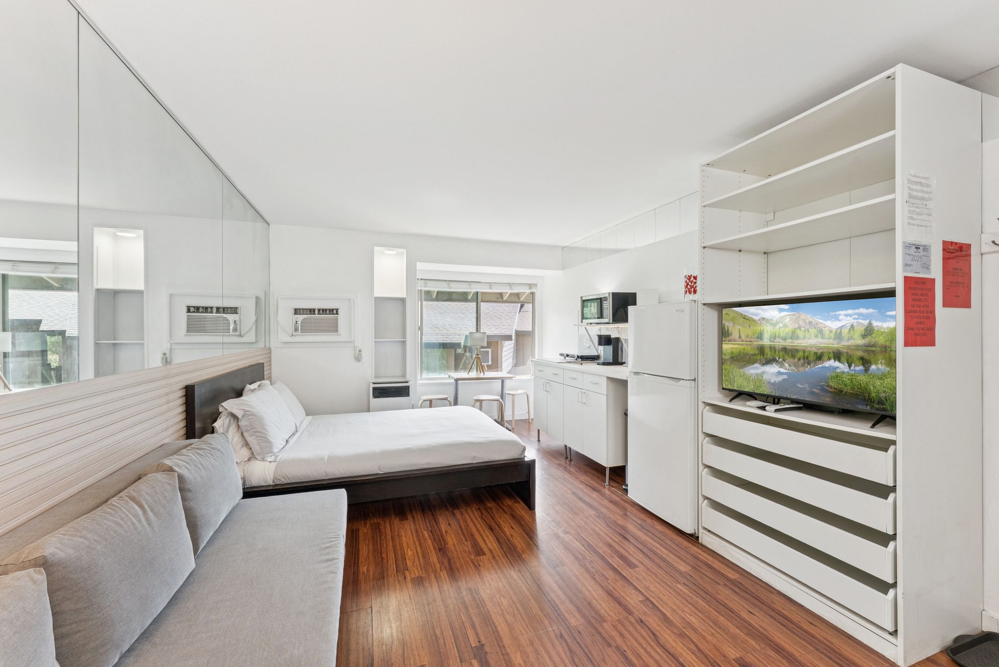 Bedroom with dark wood-style floors and freestanding refrigerator