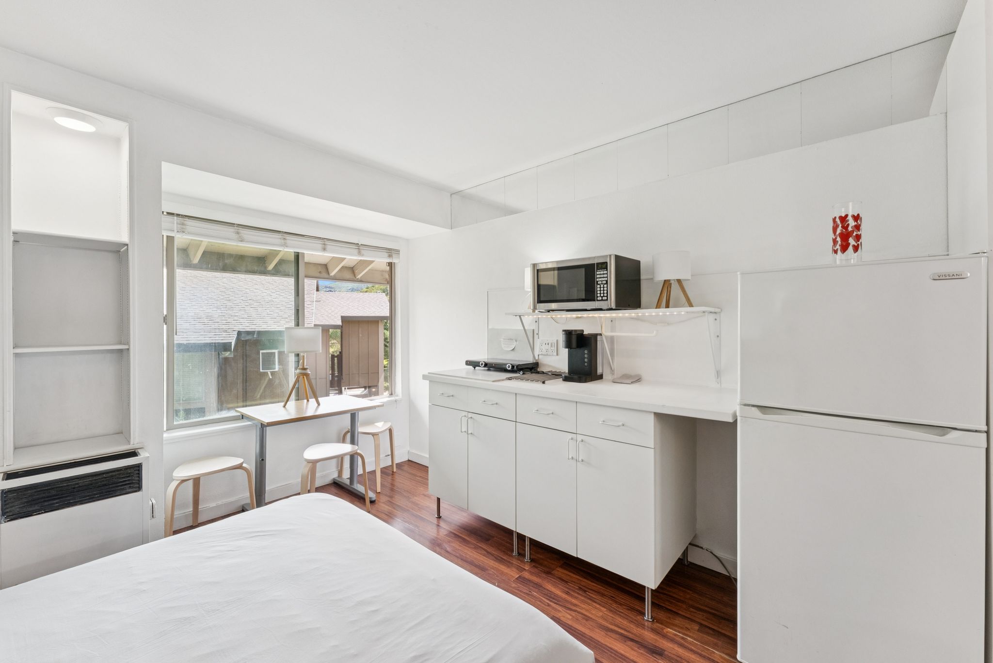 Bedroom with freestanding refrigerator, dark wood-style flooring, and heating unit
