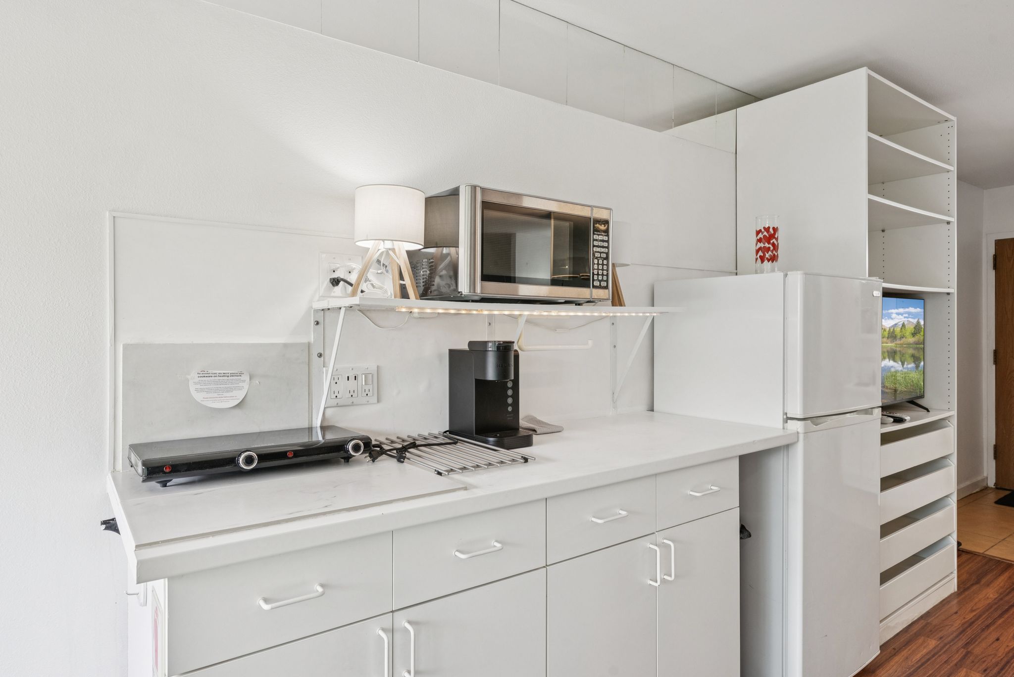 Kitchen with freestanding refrigerator, light countertops, white cabinetry, and stainless steel microwave