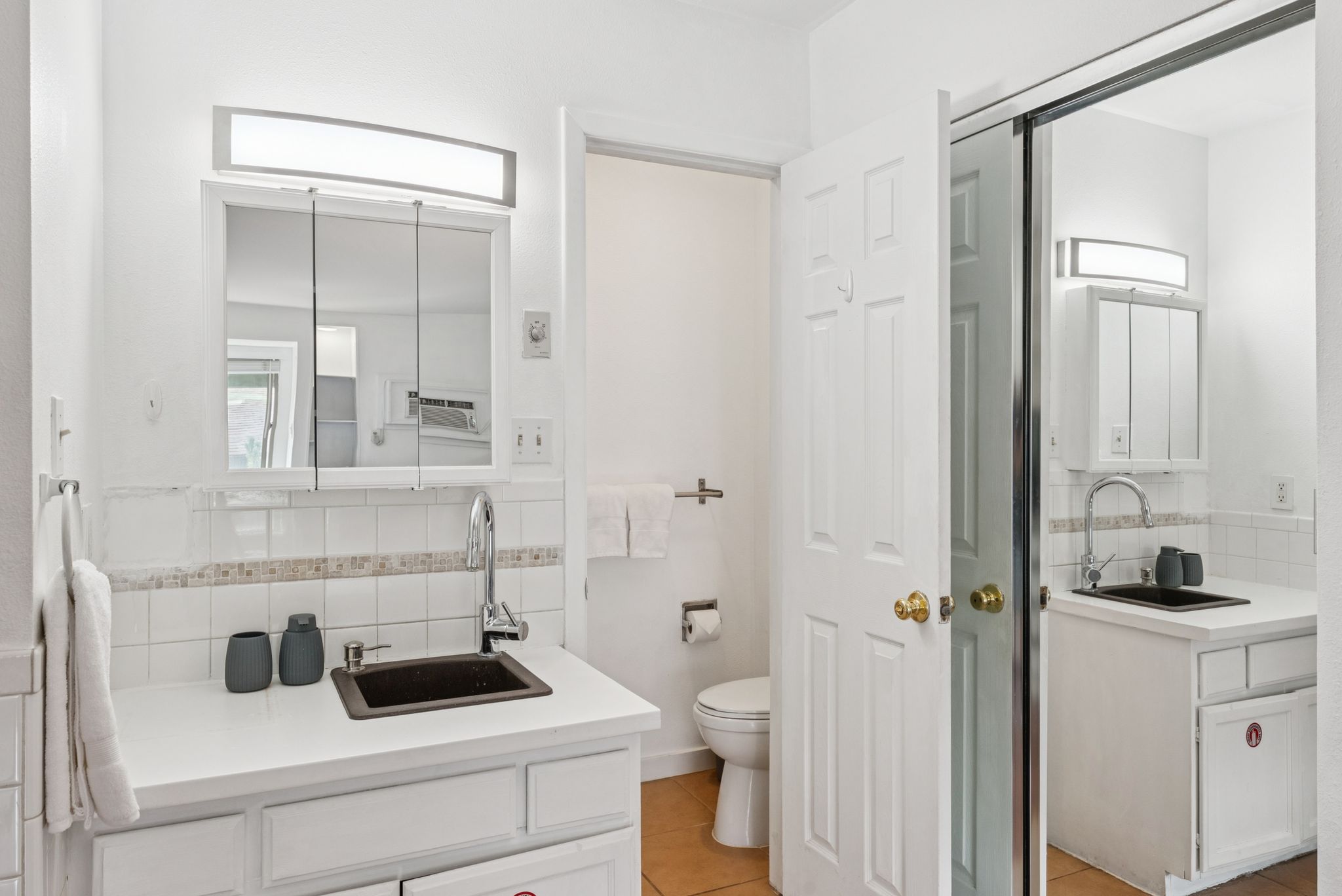 Bathroom with backsplash, two vanities, and light tile patterned floors