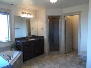 Bathroom with vanity, a garden tub, and a shower stall