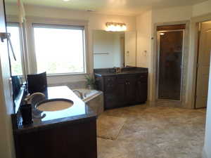 Full bath featuring two vanities, a bath, and a shower stall