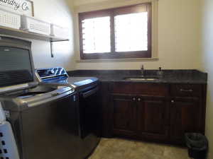 Laundry area featuring washing machine, clothes dryer, and cabinet space with sink
