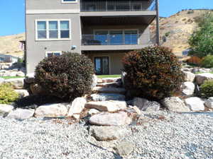 Rear view of property featuring stucco siding, a balcony, and a mountain view