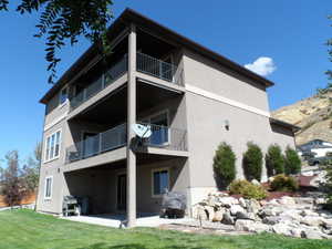 Back of property featuring a patio area, stucco siding, a yard, and a balcony
