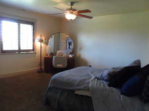 Carpeted bedroom with ceiling fan and baseboards