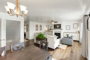 Living area with wood finished floors, a fireplace, suspended lighting, and a ceiling fan