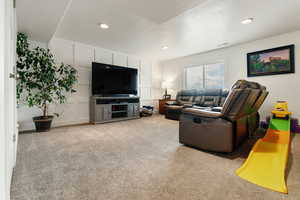 Living area featuring light carpet, recessed lighting, and a decorative wall