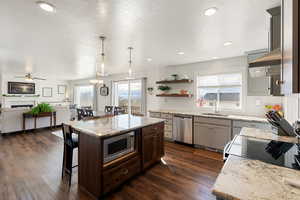 Kitchen featuring a breakfast bar area, light stone countertops, backsplash, a center island, and open floor plan