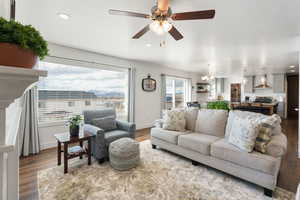 Living area featuring dark wood-style floors, suspended lighting, and ceiling fan