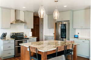 Kitchen with stainless steel appliances, backsplash, light stone counters, and dark wood finished floors