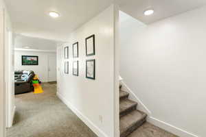 Hall featuring light colored carpet and baseboards